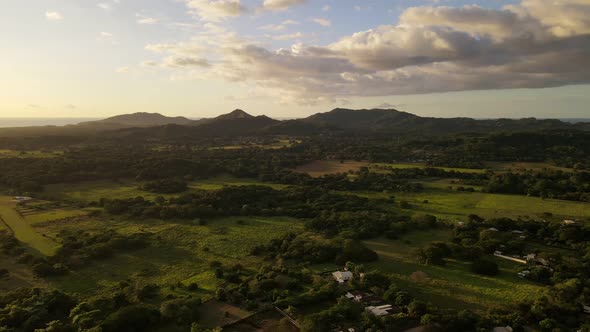 Mountainous landscape between central American farmland and the pacific ocean during sunset. Aerial