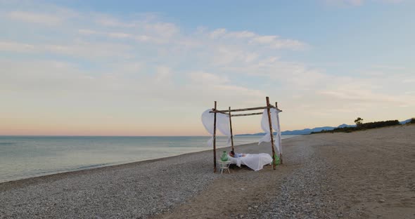 Young girl sleeps in a canopy bed at sunset on the beach near the ocean