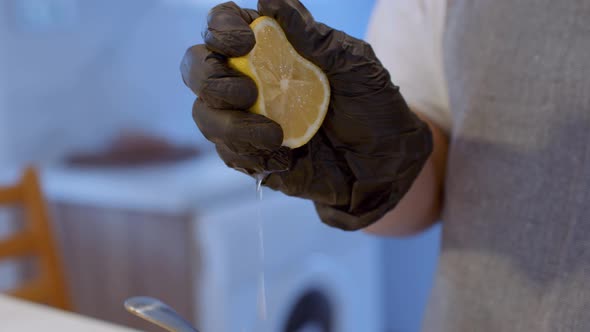 Hand Squeezing Juicy Lemon  Against Dark Background