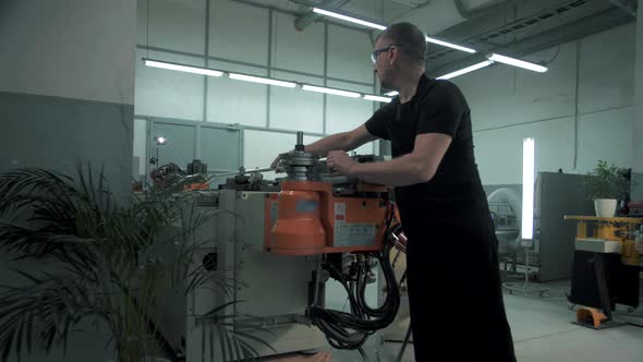 Team of engineers in the factory work at a CNC machine that bends metal products into any shape