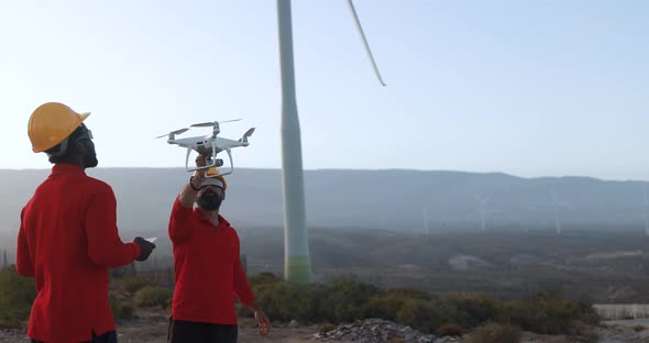 Multiracial engineer men working together on a windmill farm with digital tablet and drone
