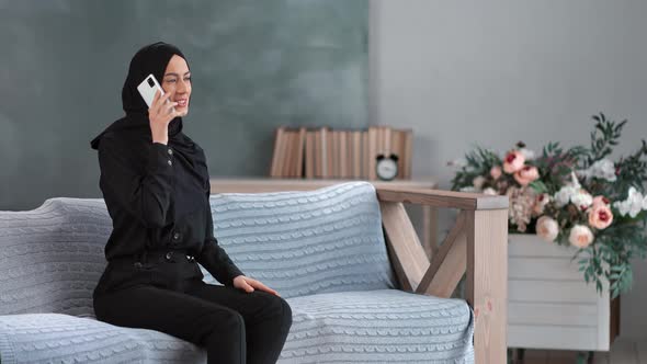 Cheerful Turkish Woman Communicating Smartphone on Couch