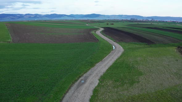 Long And Winding Dirt Road Through Vast Meadow Landscape. aerial drone