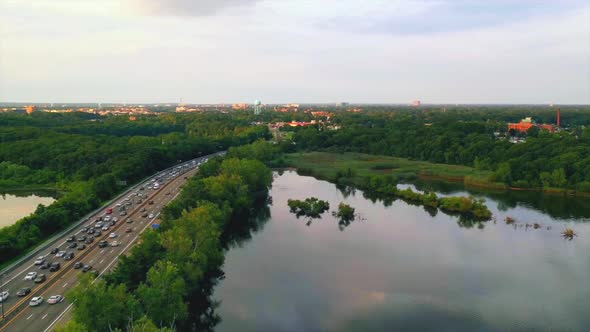 dramatic aerial hyper lapse pull away over a lake with traffic on the highway near by on the left, d