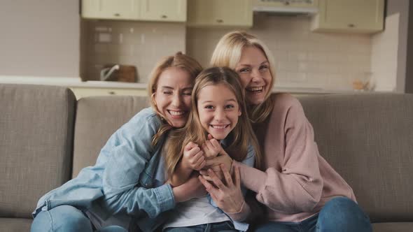 Three Generations of Women Look at Camera Cute Little Girl Hug Mom and Granny Enjoy Time at Home