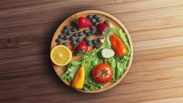 Variety of Color Fruits and Berries and Vegetables with Greens are Rotating on the Plate