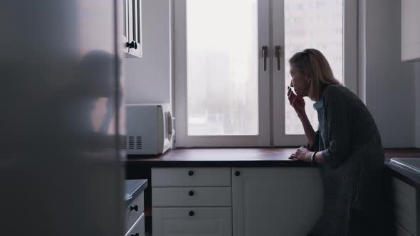 Depressed Lonely Elderly Woman Leaning on the Kitchen Cupboard