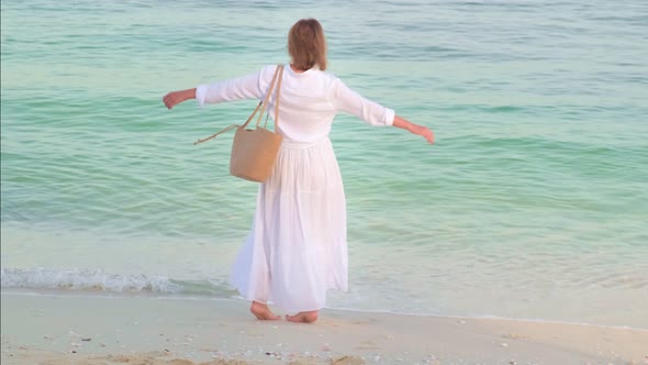 Happy Woman in the Long White Dress Spinning and Dancing at the Ocean Sea Beach