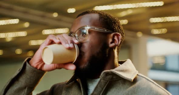 AfricanAmerican Man Drinks Coffee While Walking Around Business Center of City