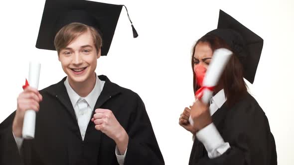 Caucasian Young Graduate Male Happily Dancing and Rejoicing with African American Female in Black