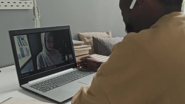 Man Talking with Muslim Woman on Video Call on Laptop