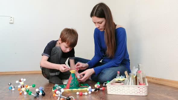 Mom and Son Applied the Chemicals Into the Funnel for the Experiment with a Clay Volcano.