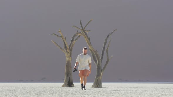 Lone Traveler With Camera On Hand Walking In The Salt Pan At Sossusvlei In Namib-Naukluft National P