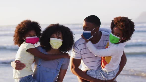 Portrait of african american family wearing face masks at the beach