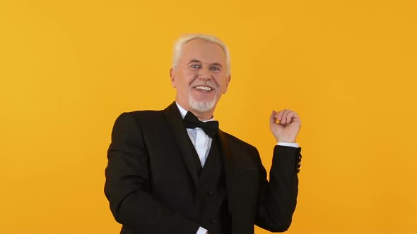 Joyful Handsome Pensioner Dancing on Orange Background, Smiling on Camera, Fun