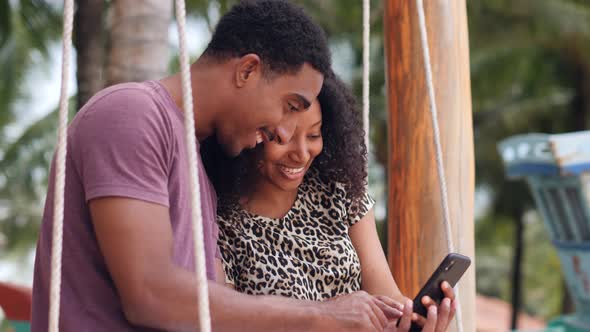 Beautiful Young African Couple Happily Watching Their Photos in a Smartphone