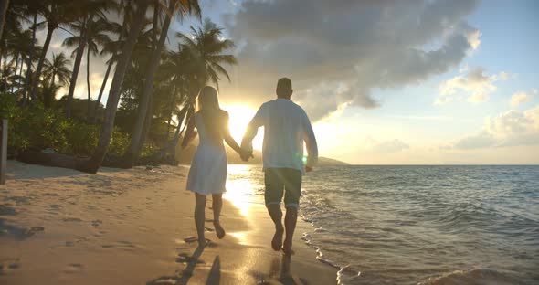 Wonderful Tropical Evening Near Ocean Two Young People Running Along the Sandy Beach Hand in Hand