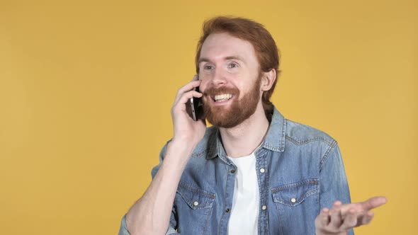 Excited Redhead Man Talking on Phone, Yellow Background