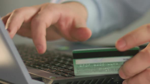 Businessperson Typing Bank Card Number on Laptop, Close-Up of Man's Fingers