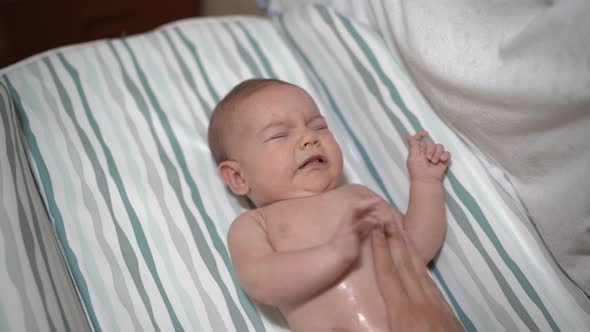 Newborn Baby Lying on the Bed is Massaged the Tummy