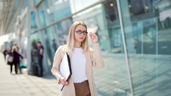 young business lady walking on a city street on an urban background of a modern office building