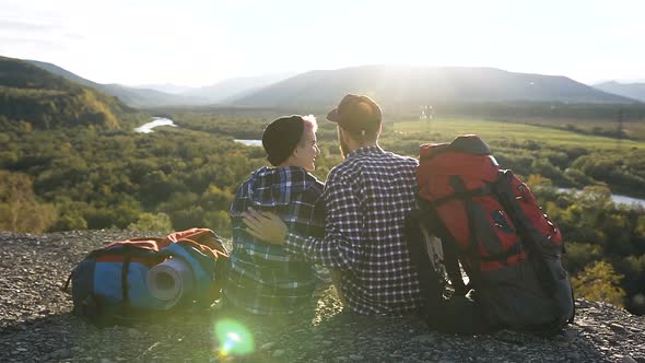 Happy Couple Sitting on the Ground During Traveling in the Mountain