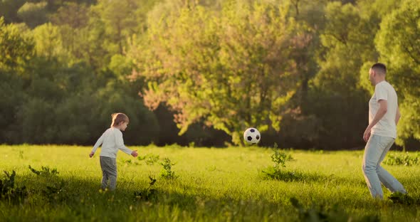 Father with Two Sons Playing Football in the Meadow