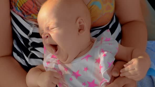 Sleepy Baby Yawning When Lying on Mothers Lap Outdoor