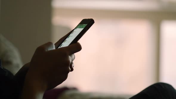 Woman texting in her smartphone using an instant messaging app, side view of unrecognizable girl usi