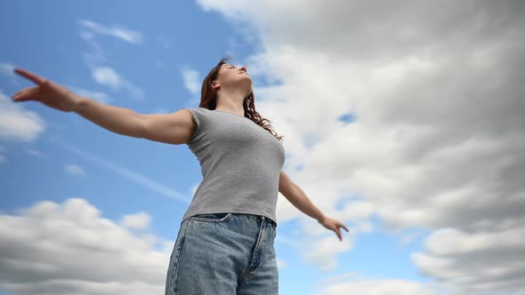 Caucasian Woman Spread Her Arms Like Wings Against a Cloudy Sky