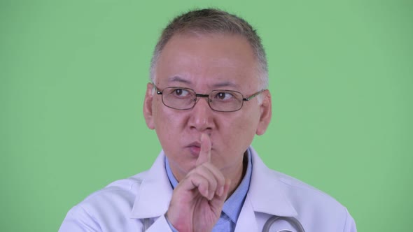 Serious Mature Japanese Man Doctor with Finger on Lips