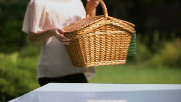 Lady Putting Picnic Basket on Table, Preparing for Family Dinner Outdoors