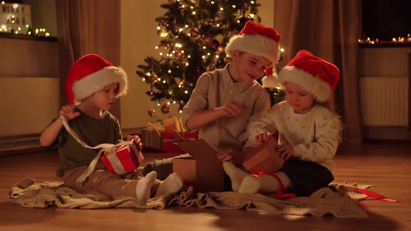 Happy Children Opening Christmas Gifts at Home