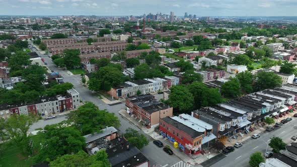 Urban American city neighborhood. Baltimore skyline in distance. Rowhouses by street. Aerial pullbac