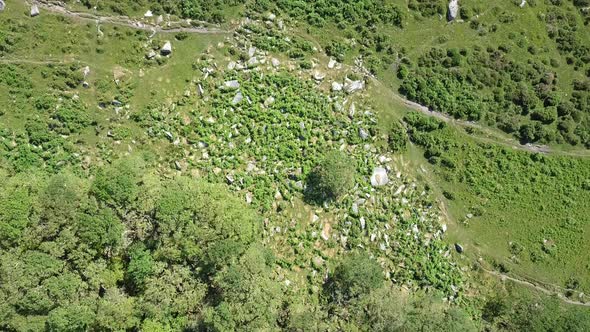 Wide aerial birdseye shot of a rocky area surrounded by green bracken trees and grassy moorland, Dar