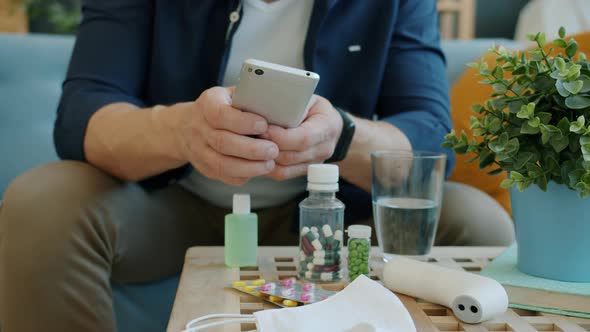 Slow Motion of Male Hands Using Smartphone Near Table with Antiviral Drugs, Hand Sanitizer and alt