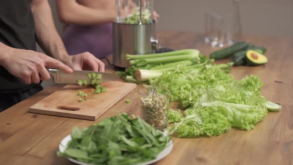 Man cuts the ingredients for making green vegetable smoothies. healthy food concept