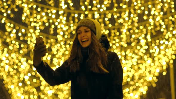 Portrait of a Happy Girl on a Evening Street Decorated with Christmas Lights