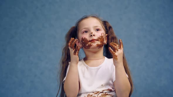 Smiling child licking chocolate off her fingers. 