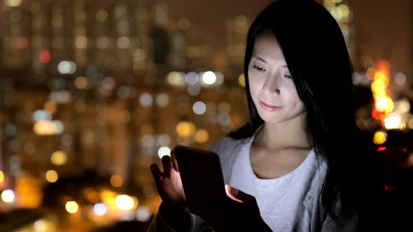 Woman working on smart phone at night