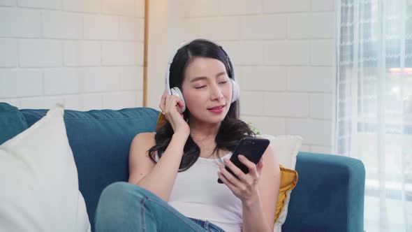 Asian woman listening music and using smart phone, female using relax time lying.
