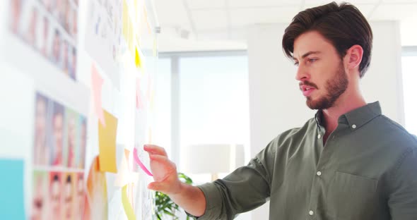 Executive reading sticky notes on glass wall