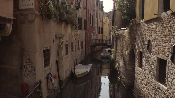 Wide tilt up shot of historic water canal street Cale Castagna with brick wall, Venice, Italy