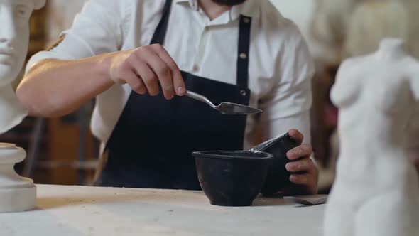 Sculptor Adding Special Dry Substance to Bowl to Prepare Glue for Sculpture