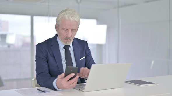 Happy Old Businessman Talking on Smartphone in Office