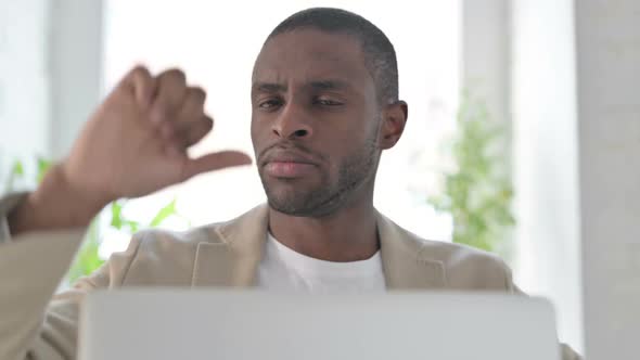 Close Up of African Man with Laptop Showing Thumbs Down