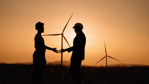 Silhouette Man in White Helmet and Black Suit Shaking Hands with Indian Engineer