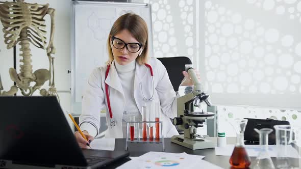  Medical Worker Writing Down Marks During Her Work with Flask Filling of Transparent Liquid