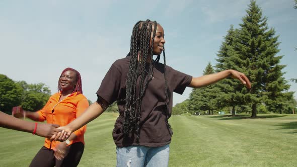 Joyful Afican Family with Teenage Girls Having Fun Dancing on Park Lawn