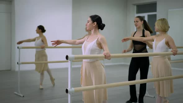 Side View Concentrated Ballerinas at Barre Rehearsing Leg Movement in Studio Indoors